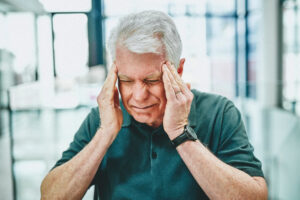 elderly man squeezing his temples with his hands